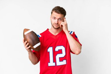 İzole edilmiş beyaz arka plan üzerinde ragbi oynayan genç beyaz bir adam bir fikir düşünüyor.