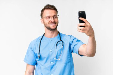 İzole edilmiş beyaz arka planda genç bir hemşire selfie çekiyor.