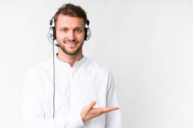 Tele pazarlamacı beyaz bir arka planda kulaklıkla çalışan beyaz bir adam gülümseyerek bir fikir sunuyor.