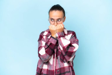 Genç Arap kadın mavi arka planda izole edilmiş gergin ve korkmuş bir şekilde elleriyle suni teneffüs yapıyor.