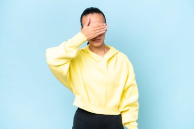 Genç bir Arap kadın mavi arka planda tek başına gözlerini elleriyle kapatıyor. Bir şey görmek istemiyorum.