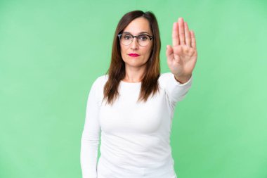 Orta yaşlı kadın izole edilmiş krom anahtar arka planda durma hareketi yapıyor.