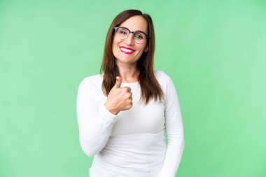 Orta yaşlı bir kadın izole edilmiş krom anahtar geçmişi var. Baş parmak işareti yapıyor.