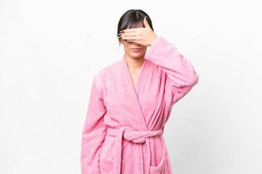 İzole edilmiş beyaz arka planı olan bornozlu genç bir kadın gözlerini elleriyle kapatıyor. Bir şey görmek istemiyorum.