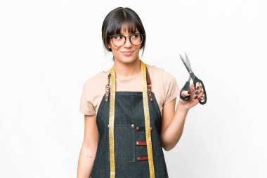 İzole edilmiş beyaz arka plan üzerinde genç beyaz terzi yan bakıyor ve gülümsüyor.