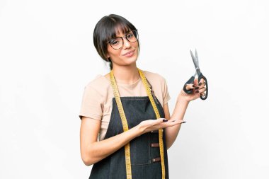 İzole edilmiş beyaz arka plan üzerinde genç beyaz terzi, davet edilmek için ellerini yana uzatıyor.