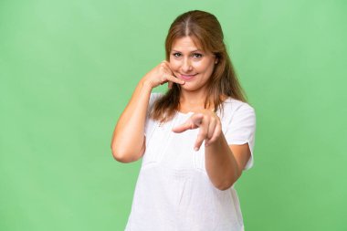 Orta yaşlı beyaz bir kadın izole edilmiş bir geçmişi var. Telefon hareketleri yapıyor ve ön tarafı işaret ediyor.