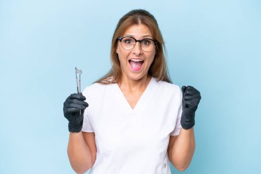 Orta yaşlı dişçi mavi arka plan üzerinde araçlar tutuyor galibiyeti kutluyorlar