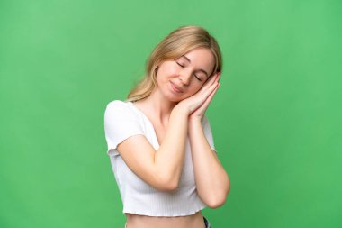 Soyutlanmış arka planda genç bir İngiliz kadın uyku jesti yapıyor.