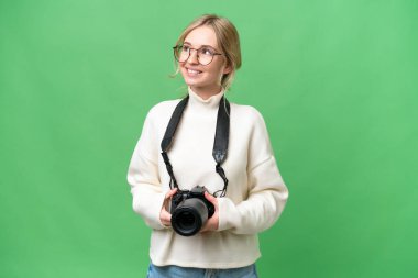 Genç fotoğrafçı İngiliz kadın izole edilmiş arka planda gülümserken yukarı bakıyor