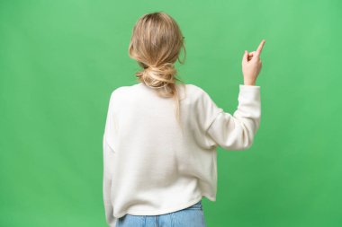 Genç fotoğrafçı İngiliz kadın izole edilmiş arka planda işaret parmağıyla işaret ediyor.