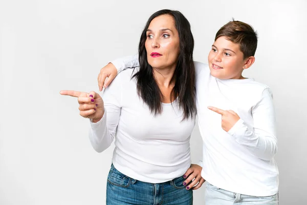 一个白人小孩 和他的妈妈一起在一个孤立的白色背景下 手指指向旁边 — 图库照片