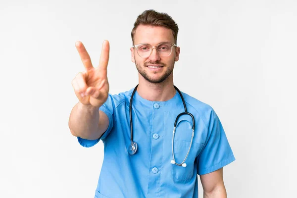 Junger Krankenpfleger Vor Isoliertem Weißem Hintergrund Lächelt Und Zeigt Siegeszeichen — Stockfoto