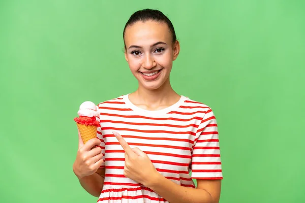 Young Arab woman with a cornet ice cream over isolated background pointing to the side to present a product
