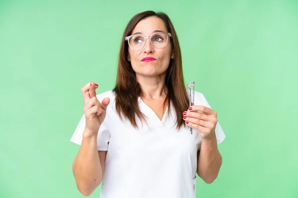 Dentist caucasian woman over isolated chroma key background with fingers crossing and wishing the best