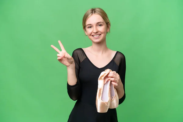 Young English woman practicing ballet over isolated background smiling and showing victory sign