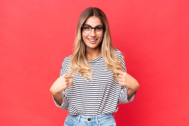 Genç Uruguaylı kadın, kırmızı arka planda yalıtılmış ve şaşırmış bir yüz ifadesi var.