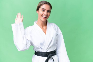 Genç Uruguaylı kadın izole edilmiş arka planda karate yapıyor. Mutlu bir ifadeyle selamlıyor.
