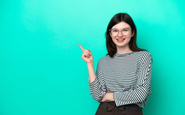 Yeşil arka planda izole edilmiş genç Rus kadın mutlu ve yukarıya bakıyor.