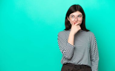 Yeşil arka planda izole edilmiş genç bir Rus kadının şüpheleri ve kafa karıştırıcı bir yüz ifadesi var.