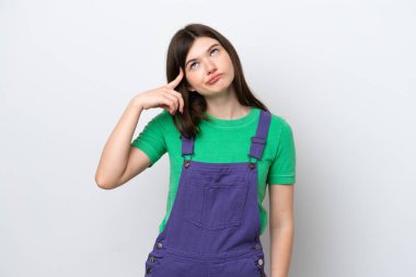 Genç Rus kadın mavi arka planda izole edilmiş. Delilik jesti yapıyor. Parmağını kafaya koyuyor.