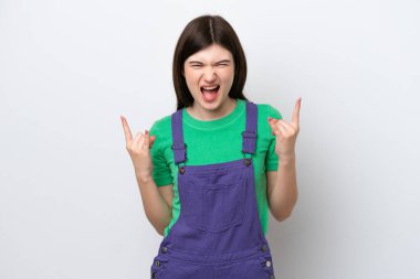 Mavi arka planda izole edilmiş genç bir Rus kadın boynuz hareketi yapıyor.