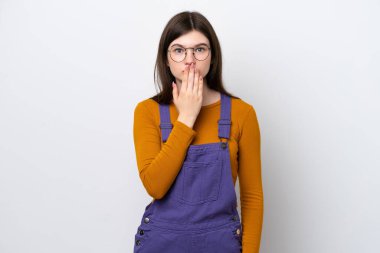 Genç Rus kadın mavi arka planda izole edilmiş. Ağzını eliyle kapatıyor.