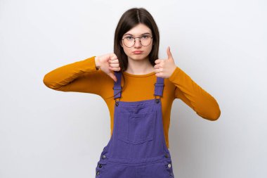 Mavi arka planda izole edilmiş genç bir Rus kadın iyiye-kötüye işaret veriyor. Evet ya da hayır arasında kararsız