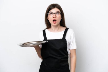 Tepsisi beyaz arka planda izole edilmiş genç Rus kadın aşçı yukarı bakıyor ve şaşırmış bir ifadeyle