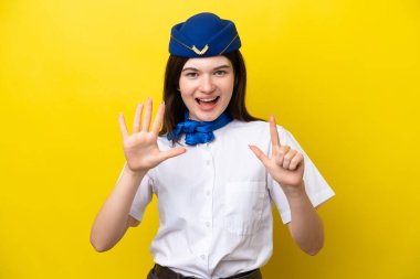 Uçak hostesi Rus kadın sarı arka planda izole edilmiş yediyi parmaklarıyla sayıyor.