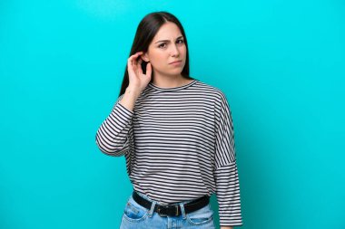 Kafkasyalı genç bir kadın mavi arka planda izole edilmiş. Şüpheleri var.