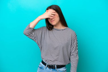 Kafkasyalı genç bir kadın mavi arka planda izole edilmiş, baş ağrısı var.