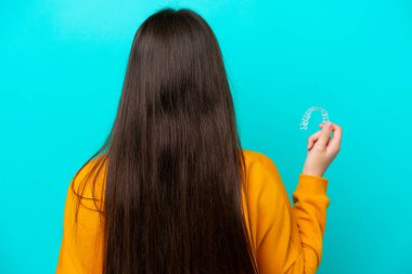 Arka planda mavi arka planda görünmez diş telleri tutan beyaz bir kadın var.