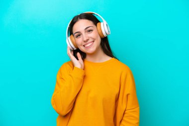 Young girl isolated on blue background listening music