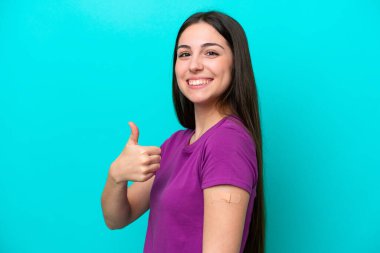 Young girl with band-aids isolated on blue background with thumbs up because something good has happened