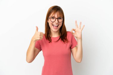 Kızıl saçlı kız beyaz arka planda izole edilmiş. Tamam işareti gösteriyor.
