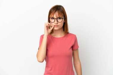 Kızıl saçlı kız beyaz arka planda izole edilmiş. Sessizlik işareti gösteriyor.