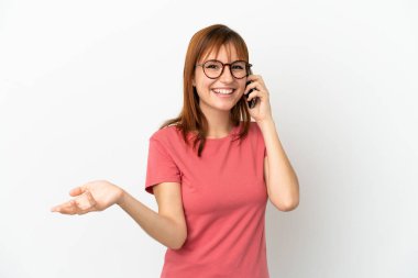 Kızıl saçlı kız beyaz arka planda izole edilmiş. Cep telefonuyla biriyle sohbet ediyor.