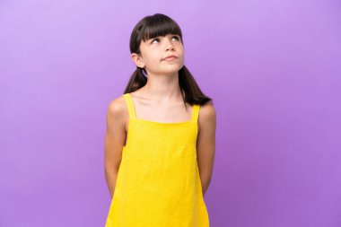 Küçük beyaz çocuk mor arka planda izole edilmiş ve yukarı bakıyor.