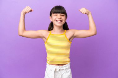 Mor arka planda izole edilmiş beyaz bir çocuk güçlü bir jest yapıyor.