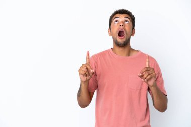 Beyaz arka planda izole edilmiş yakışıklı Brezilyalı adam şaşırmış ve yukarı bakıyor.