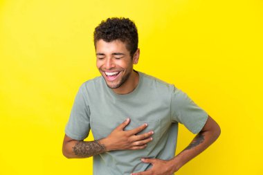 Sarı arka planda izole edilmiş yakışıklı Brezilyalı adam çok gülümsüyor.