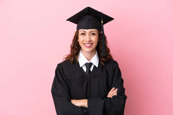Young university graduate woman isolated on pink background keeping the arms crossed in frontal position