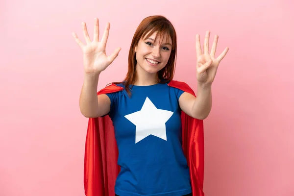 Super Hero redhead girl isolated on pink background counting nine with fingers