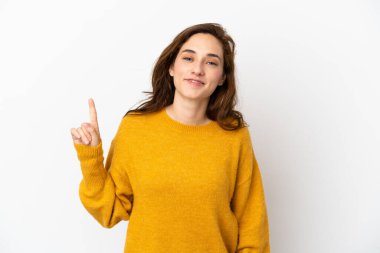 Beyaz arka planda izole edilmiş genç beyaz kadın en iyinin işareti olarak parmağını kaldırıyor ve gösteriyor.