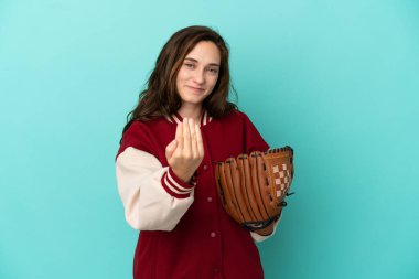 Beyzbol oynayan beyaz bir kadın, mavi arka planda izole edilmiş bir şekilde, elini kolunu sallayarak gelmesi için davet ediyor. Gelmene sevindim.