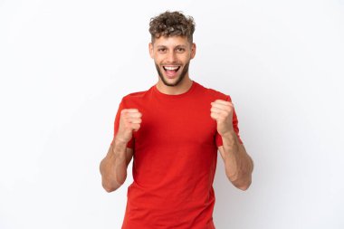 Beyaz arka planda izole edilmiş beyaz tenli yakışıklı genç adam galibiyeti kutluyor.