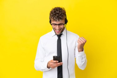 Sarı arka planda izole edilmiş bir kulaklıkla çalışan pazarlamacı sarışın adam şaşırdı ve bir mesaj gönderiyor.