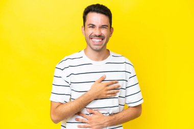 Genç yakışıklı adam, izole edilmiş sarı arka planda gülümsüyor.