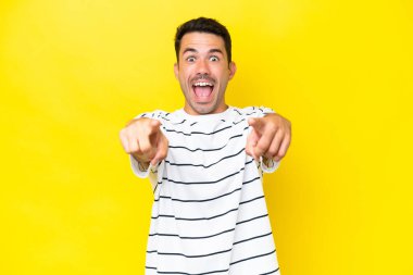 Izole sarı arka plan üzerinde genç yakışıklı adam şaşırttı ve ön işaret